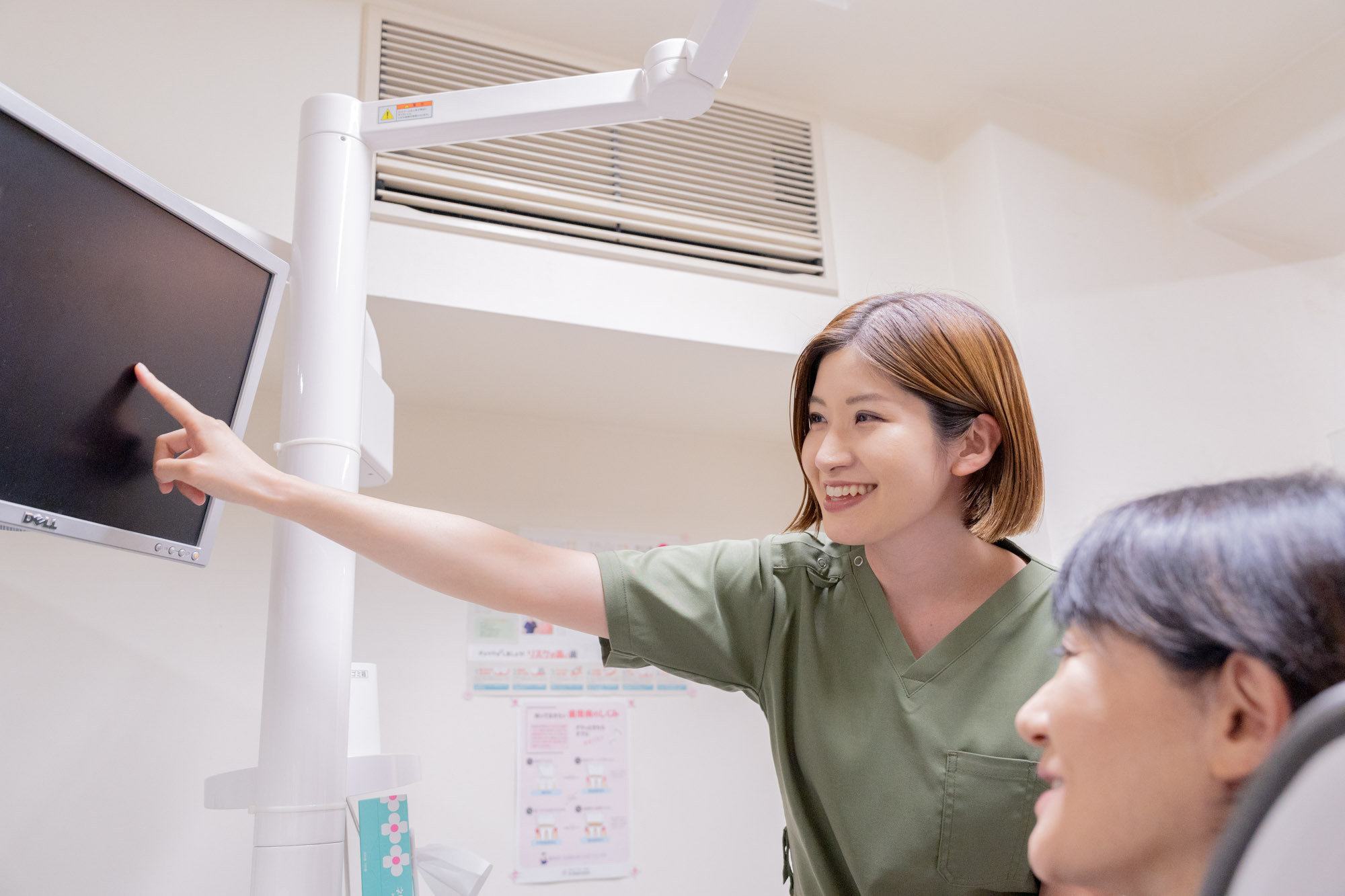 患者にモニターで説明する歯科衛生士